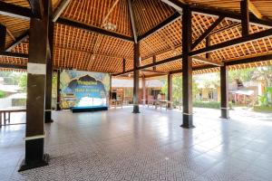 a large pavilion with a large mural on the wall at Omah Rohadi Syariah by Ndalem Beong in Borobudur