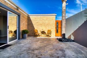 un patio con sillas, una mesa y una palmera en Magnificent Villa Load-Shedding Free! en Ciudad del Cabo