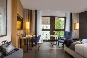 インゴルシュタットにあるMaritim Hotel Ingolstadtのベッド、テーブル、椅子が備わるホテルルームです。