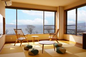 諏訪市にあるホテルすわ湖苑の椅子2脚、テーブル、窓が備わる客室です。