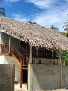 a house with a thatched roof and a staircase at Villa Beach Mentawai in Katiet