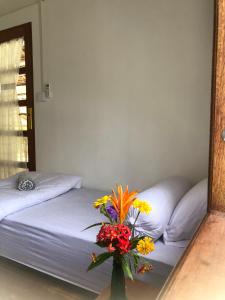 a vase of flowers sitting on a table next to a bed at Villa Beach Mentawai in Katiet