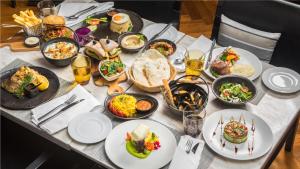 a table with plates of food and glasses of beer at Mövenpick Hotel Sukhumvit 15 Bangkok in Bangkok
