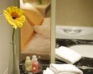 a yellow flower in a vase next to a bathroom mirror at Cosmo Hotel Hong Kong in Hong Kong