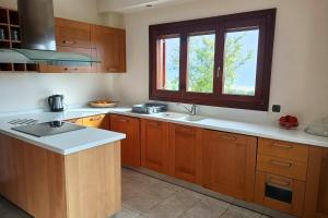 una cucina con armadi in legno, lavandino e finestra di Villa Totti a Ierissós