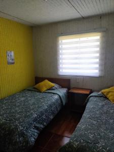 two beds in a room with a window at Cabañas Trabun Melipeuco in Melipeuco