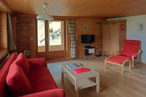 a living room with a red couch and a table at Chalet Varga in Hasliberg