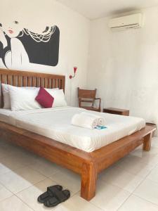 a bedroom with a wooden bed with a white mattress at Rumahku Bali Executive in Kuta