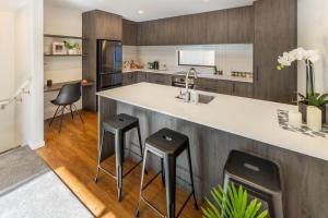 a kitchen with a counter and stools at a bar at Cozy 3 bedroom near Hagley Park w/Garage in Christchurch