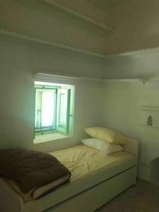 a white bedroom with a bed and a window at Kastellorizo- Entire Traditional House in Meyisti