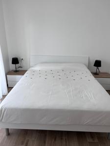 ein weißes Bett in einem Zimmer mit zwei Lampen in der Unterkunft Blue Sea in Arma di Taggia