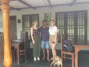 eine Gruppe von drei Personen, die in einem Zimmer mit einem Hund stehen in der Unterkunft Wilpattu homestay by Ceylon group in Wilpattu Nationalpark