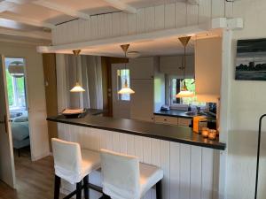 a kitchen with a counter and two white chairs at Private Big Garden double Chalet with Outside HOTTUB and BARRELSAUNA, Woodside, Nature in Voorthuizen