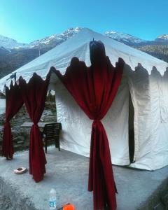 - une tente blanche avec des rideaux rouges et une table dans l'établissement Bored Ape Jispa - Camp Site, à Jispa