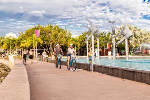 a group of people riding bikes on a sidewalk near a fountain at Cairns Central Plaza Apartment Hotel Official in Cairns
