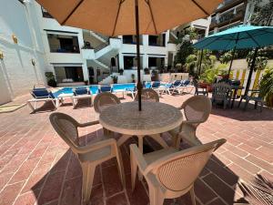 una mesa con sillas y una sombrilla en el patio en Vallarta Sun Suites, en Puerto Vallarta