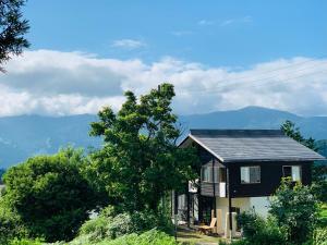 una casa su una collina con le montagne sullo sfondo di Nakao Villa (ナカオヴィラ） a Nozawa Onsen