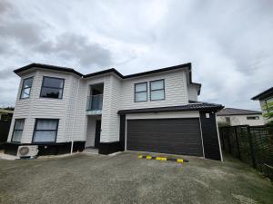 une maison blanche avec un grand garage dans l'établissement Quality Stay Private Guest Room in Auckland, à Auckland