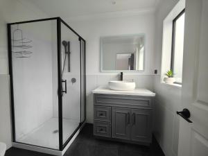 uma casa de banho com um lavatório e uma cabina de duche em vidro. em Quality Stay Private Guest Room in Auckland em Auckland