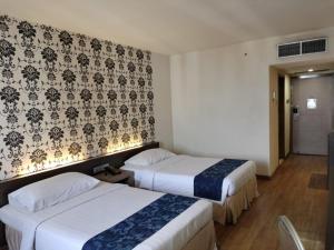 スラバヤにあるGarden Palace Hotelのベッド2台と壁が備わるホテルルームです。