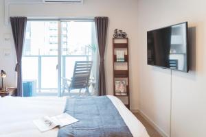 a bedroom with a bed and a television and a chair at 川HOUSE黒門 in Osaka