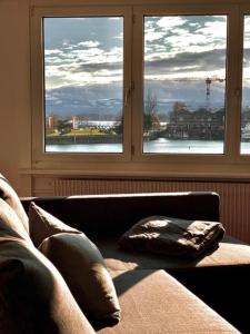 1 sofá en una sala de estar con 2 ventanas en Apartment Romanshorn von Swisspartments, en Romanshorn