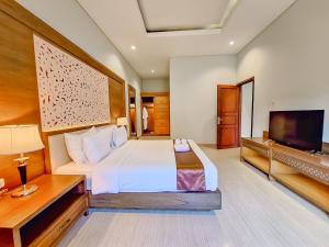 a bedroom with a bed and a flat screen tv at Sekuro Village Beach Resort in Jepara