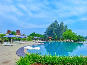 a pool at a resort with chairs and umbrellas at Sekuro Village Beach Resort in Jepara