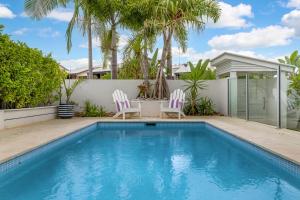 una piscina en un patio trasero con 2 sillas y una mesa en Holiday home Alex Headland, en Alexandra Headland