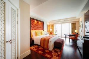 um quarto de hotel com uma cama grande e uma secretária em The Ritz - Carlton, Bangalore em Bangalore