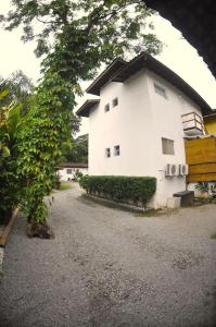 a white house with a tree in front of it at Pousada Jungle Beach Maresias in Maresias