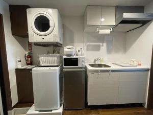 uma pequena cozinha com um lavatório e uma máquina de lavar roupa em Ao Hotel em Nago