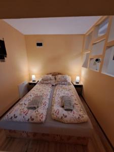 a bedroom with two beds and two night stands at Rozmaring Apartmanok in Gyula