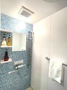 uma casa de banho com um chuveiro com azulejos azuis em Ao Hotel em Nago