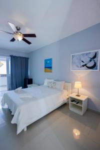 a bedroom with a white bed and a ceiling fan at Bella Vida Hotel Punta Cana in Punta Cana