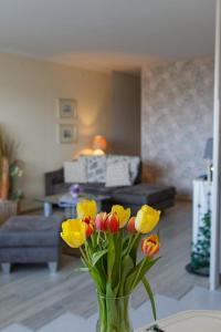 a vase filled with yellow and red tulips in a living room at Appartement "Sonnenperle" in Heiligenhafen