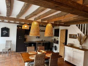 a kitchen with a wooden table and chairs and a kitchen with a stove at La Naomath - Maison d'hôtes, Hébergement insolite & Gîte in Bayeux