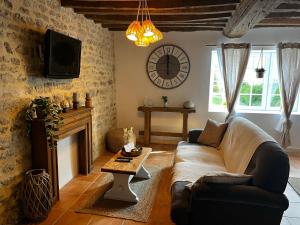 a living room with a couch and a clock on the wall at La Naomath - Maison d'hôtes, Hébergement insolite & Gîte in Bayeux
