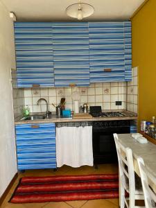 cocina con armarios azules, fregadero y mesa en CASA PERMIRRA, en Feltre