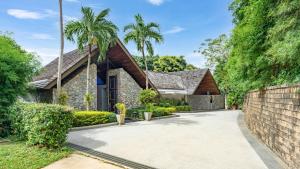 a house with a stone driveway and palm trees at Villa Rom Trai in Kathu