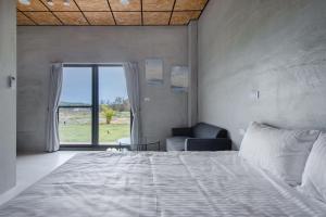 a bedroom with a bed and a chair and a window at 暮光島嶼 in Xiaoliuqiu