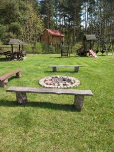 a park bench with a fire pit in the grass at Gościniec IBIS in Czarna Wieś