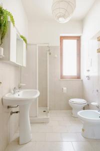 uma casa de banho branca com um lavatório e um WC em Villa La Pineta al Mare em Erice