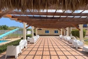 a patio with white chairs and a swimming pool at Hacienda vacacional Laureano in Los Jobitos
