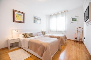 two beds in a room with white walls and wooden floors at Penthouse apartment with private parking in Zagreb