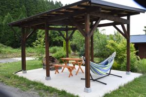 a wooden pavilion with a table and a hammock at Wakka in Minami Aso