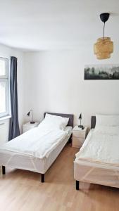 2 letti in una camera da letto con pareti bianche e pavimenti in legno di Chic Apartment with Parking place a Apolda