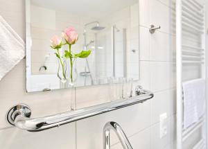 a bathroom sink with a mirror and a vase of flowers at Ferienwohnung Popeye in Neddesitz