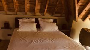 a bed with white sheets and pillows in a bedroom at La conciergerie in Namur