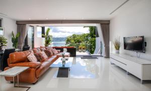 a living room with a brown leather couch and a television at Atika Villa Patong in Patong Beach